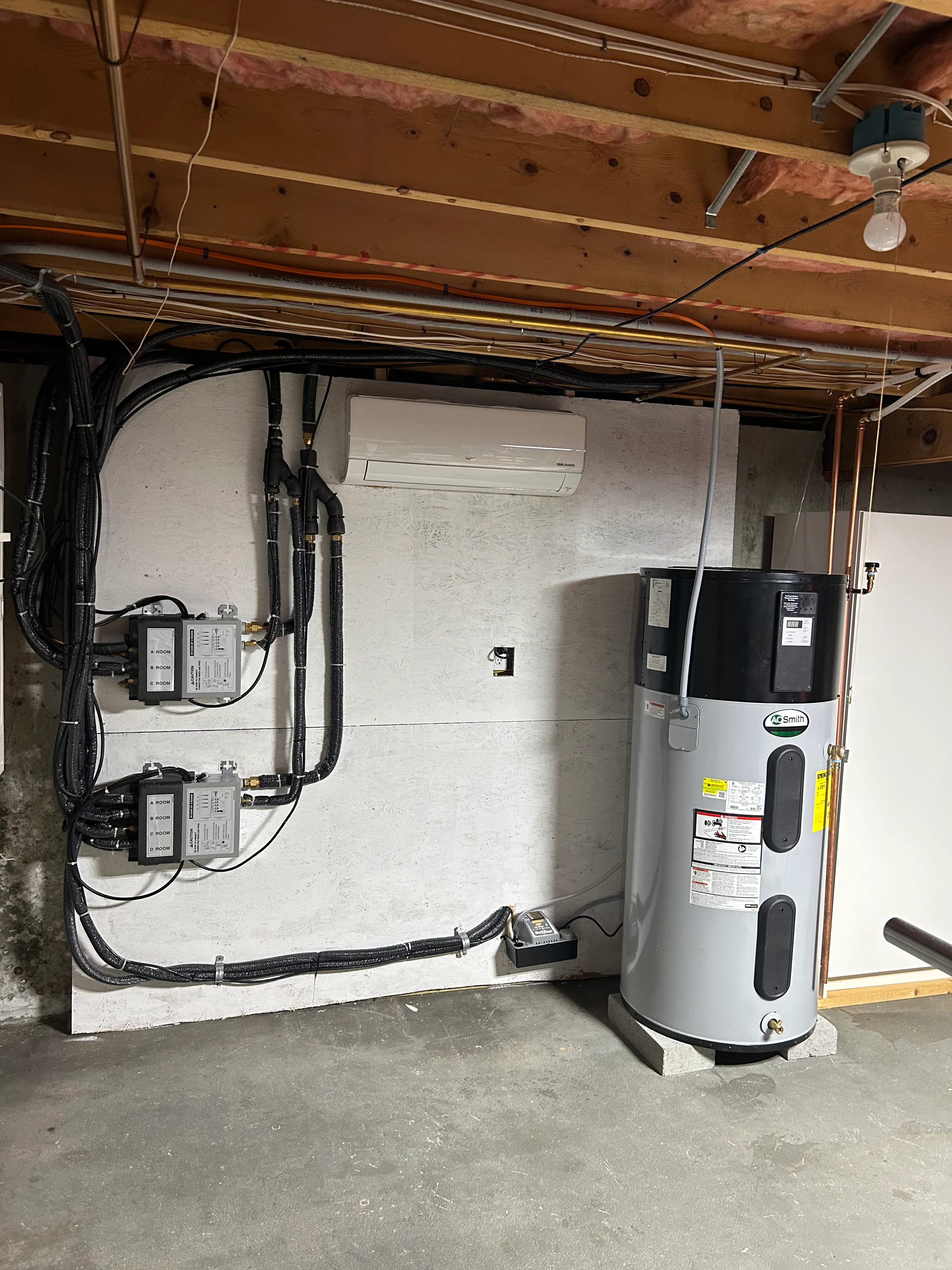 Installed hybrid heat pump water heater with electrical controls and mini-split unit in basement