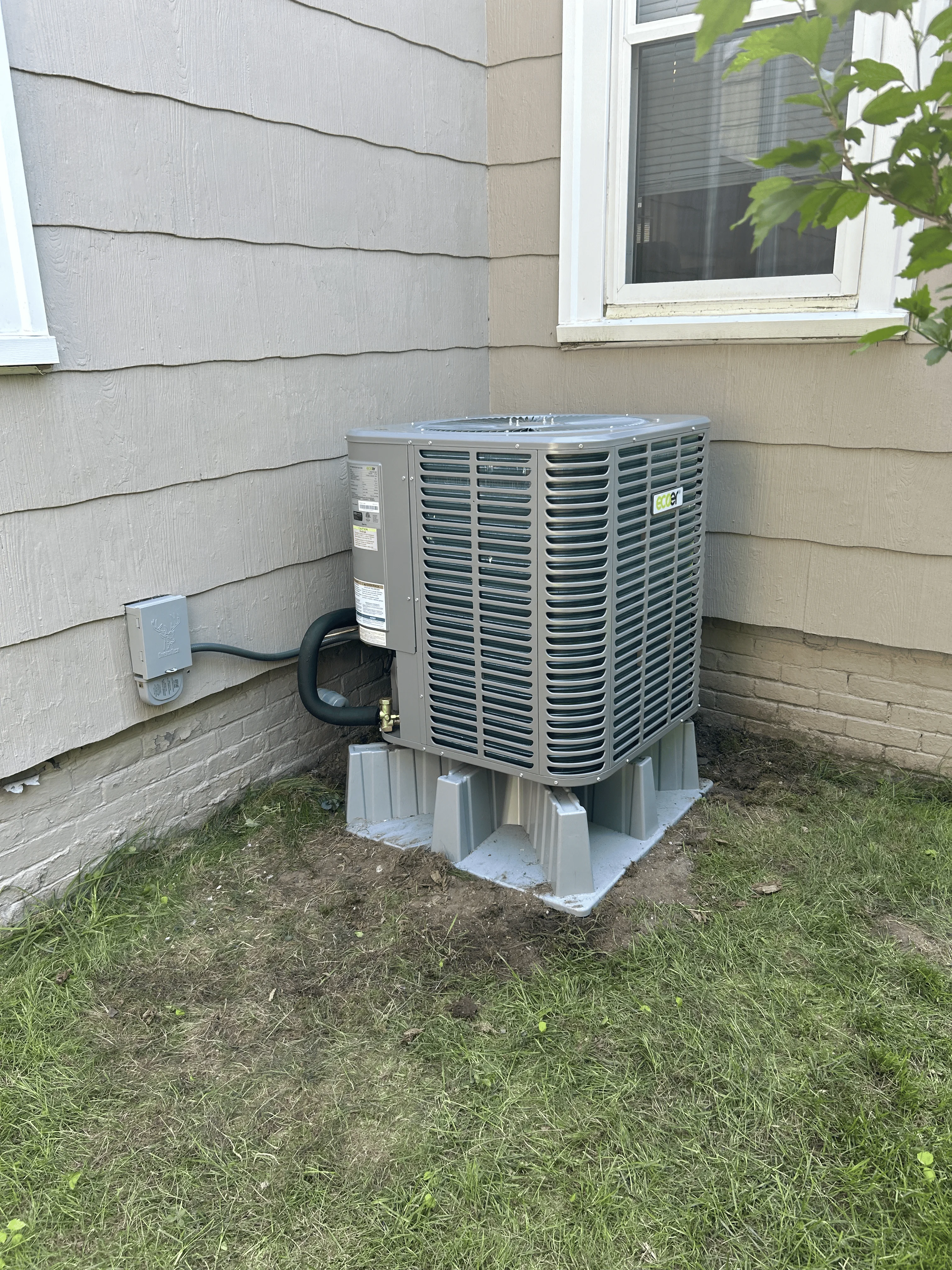 New AC condenser unit installed on concrete pad beside residential home in Rockland