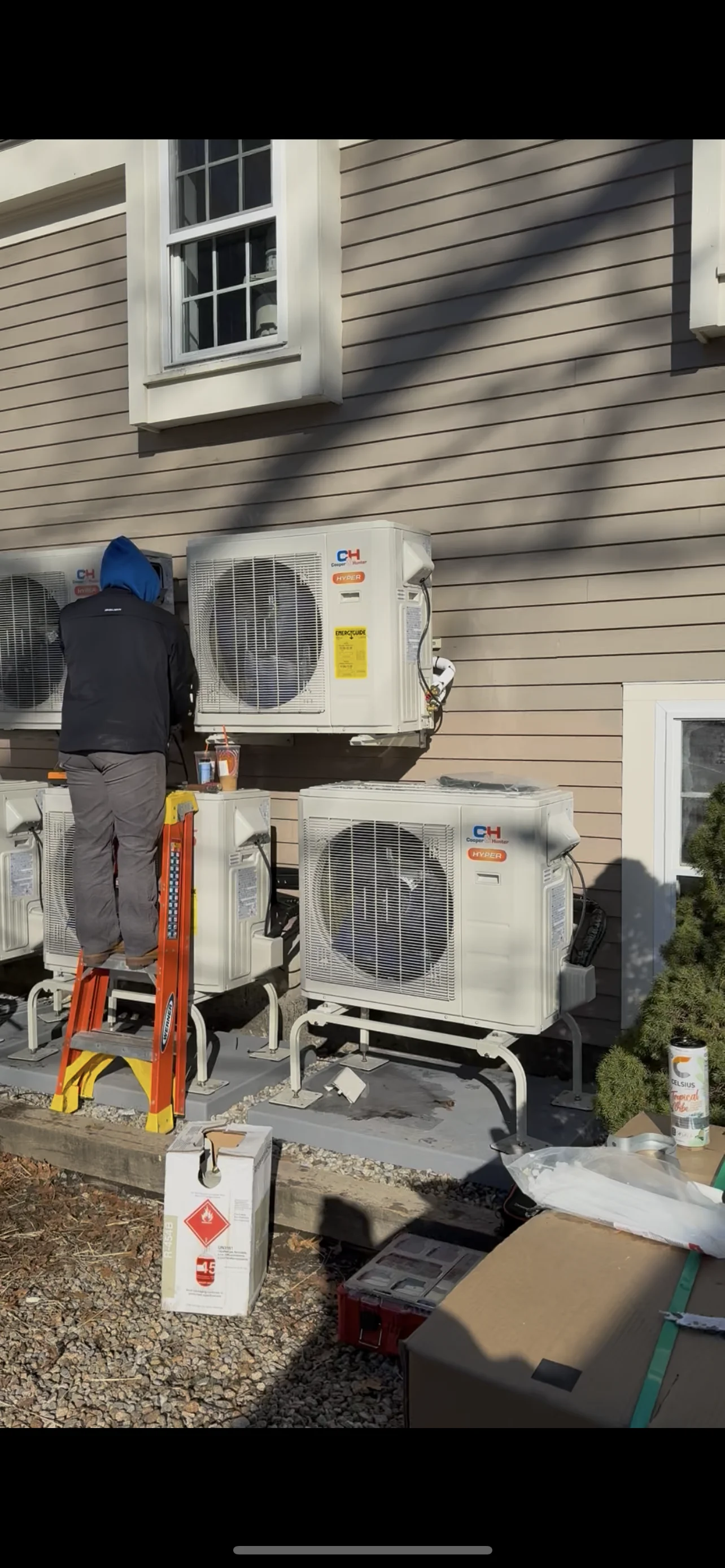 HVAC technician installing dual mini-split condenser units on home exterior