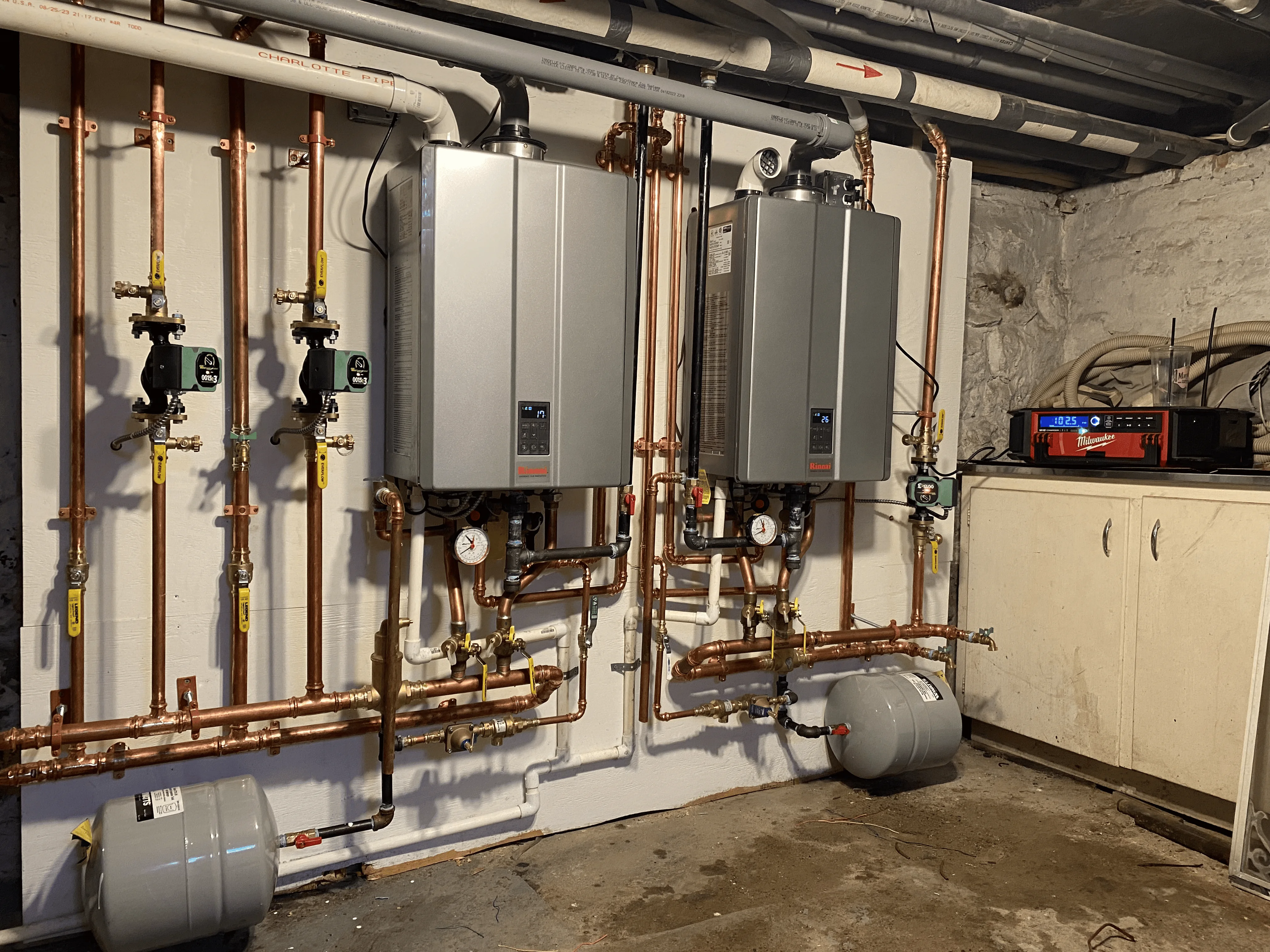 Dual tankless water heaters with copper piping and radiant heating system in basement